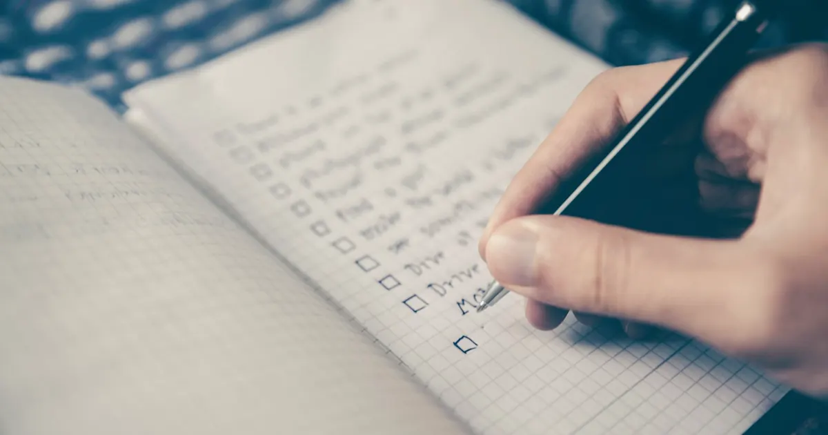 Hand filling in a checklist in a notebook