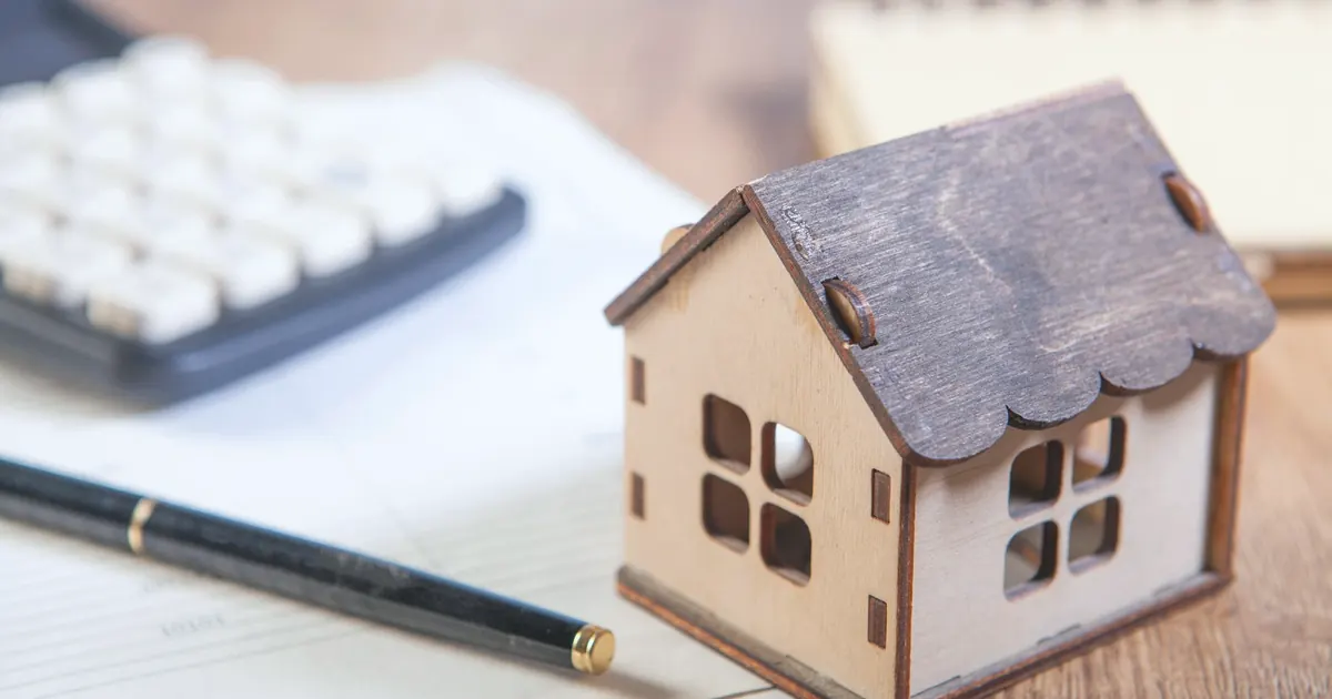 Calculator and a small wooden house on a desk