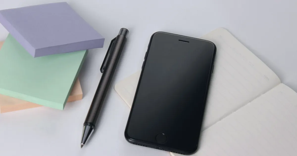 Mobile phone, pen and notebook with questions for the moving company