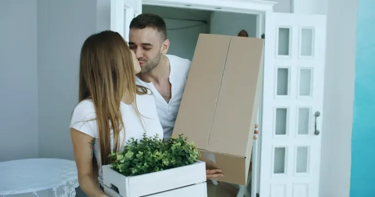 Young couple entering their new flat carrying a box