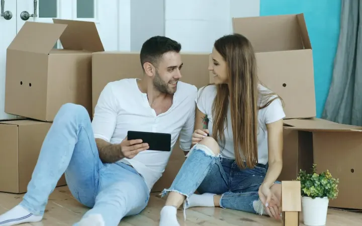 Νεαρό ζευγάρι κάθεται ανάμεσα σε κούτες μετά από φοιτητική μετακόμιση